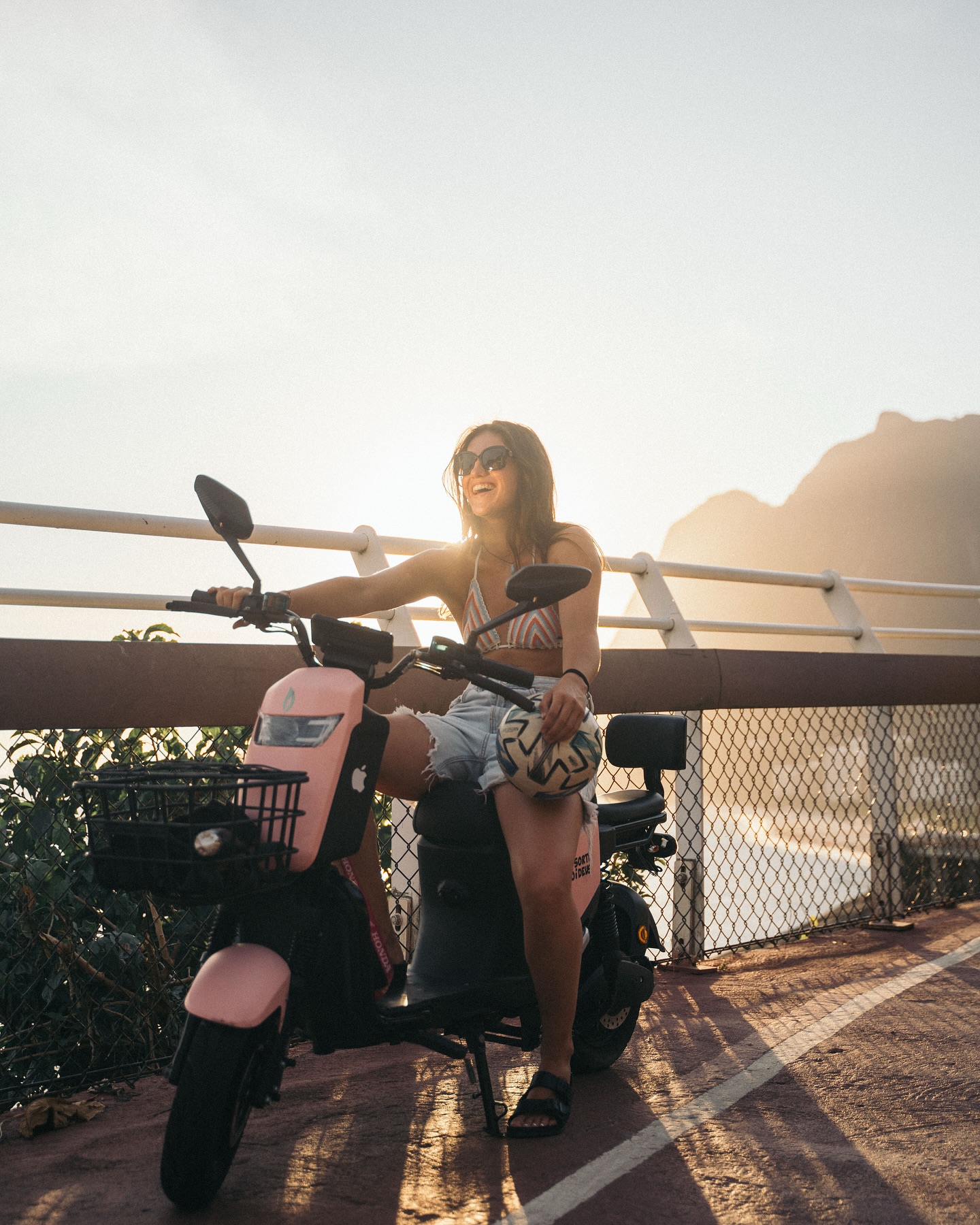 Scooter elétrica rosa ScootRio na orla do Rio de Janeiro ao pôr do sol